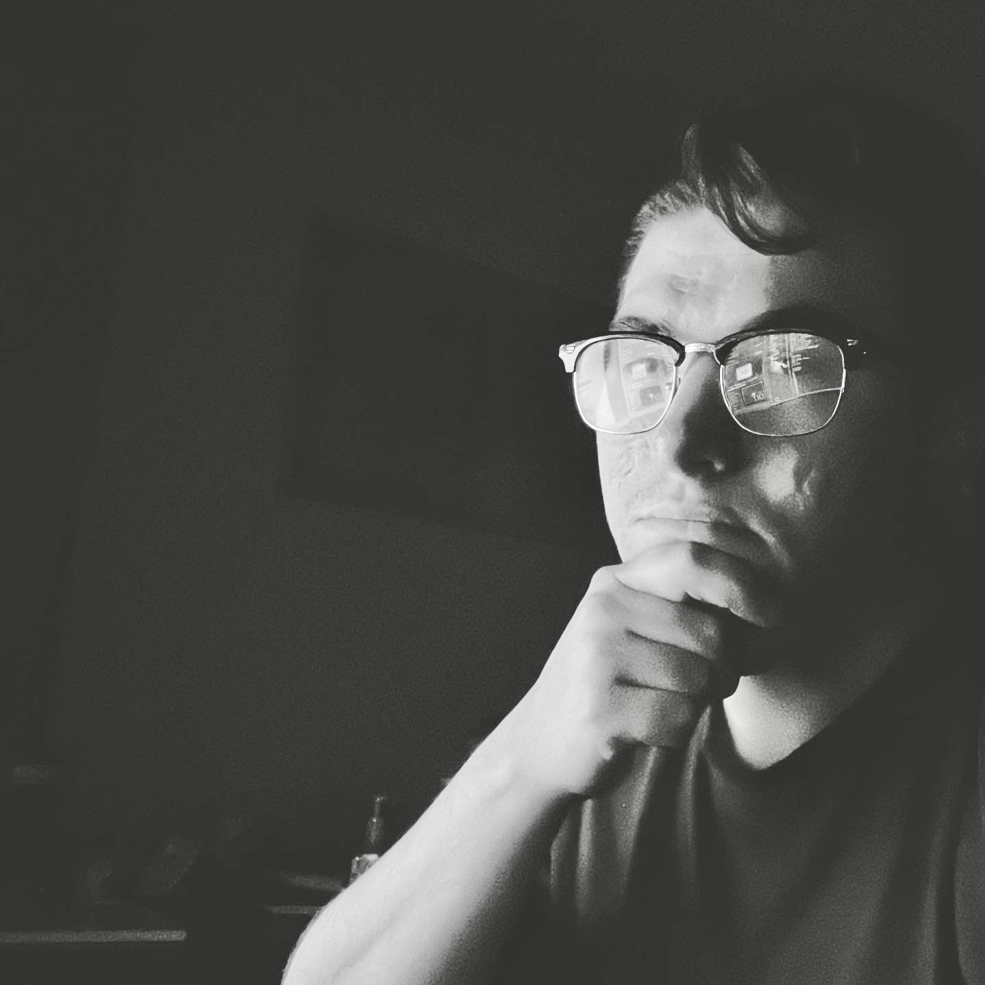 black and white picture of a man in glasses sitting at a computer